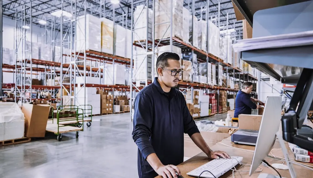 warehouse worker checking orders at computer