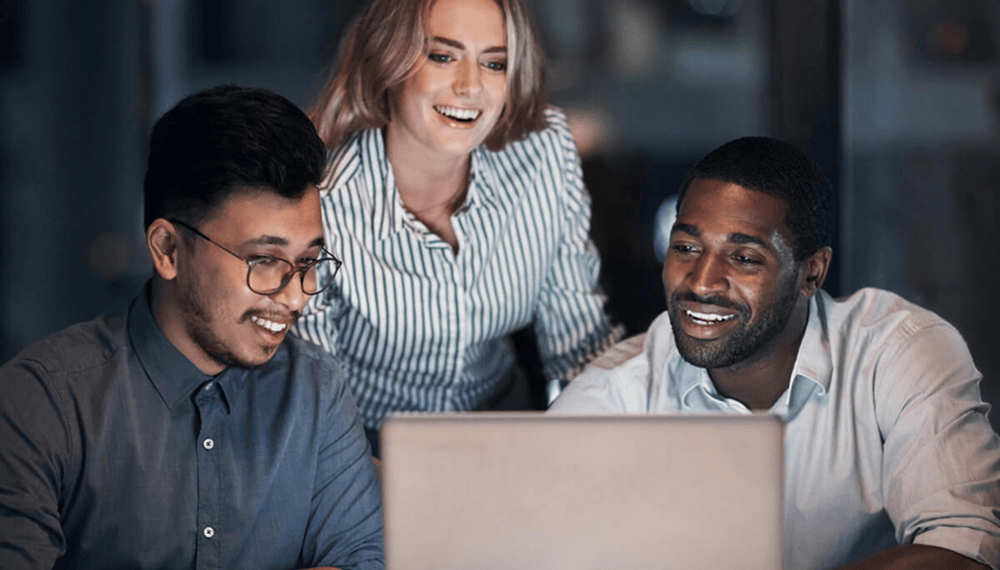Colleagues collaborating around a laptop