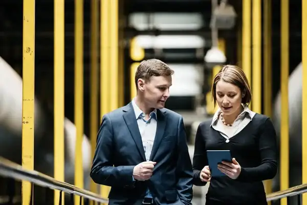 Two colleagues reviewing a tablet in a manufacturing facility