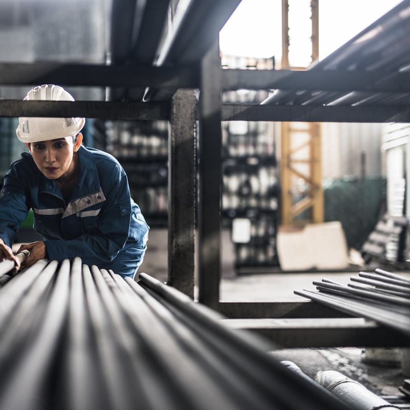 Female Steel Factory Worker at work moving steel poles