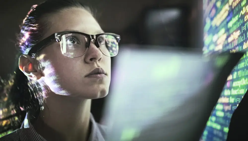 Woman wearing glasses analyzes data on a screen