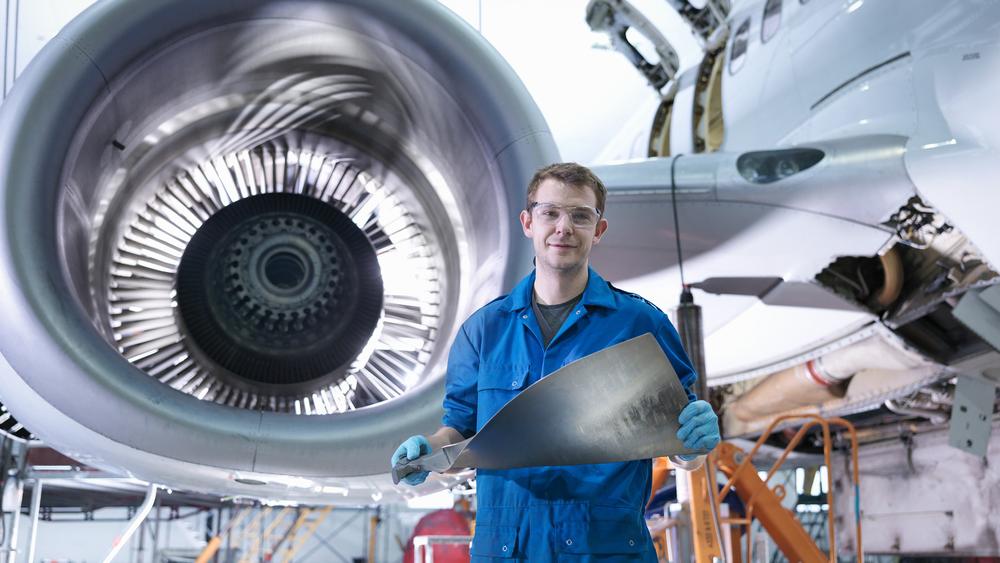 Engineer standing in front of a jet engine 