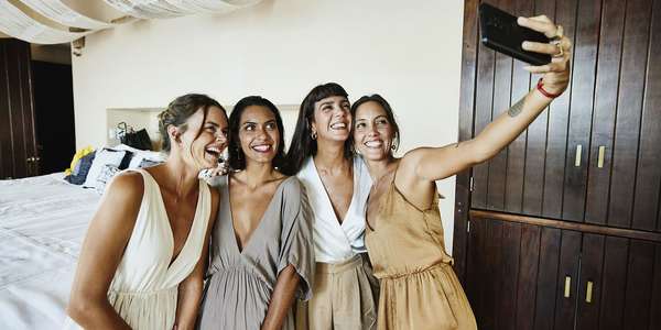Medium wide shot of smiling and laughing bridesmaids taking   selfie in luxury hotel suite Dayinlife   