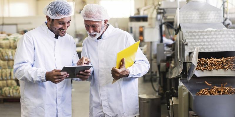 workers in uniforms looking at a tablet