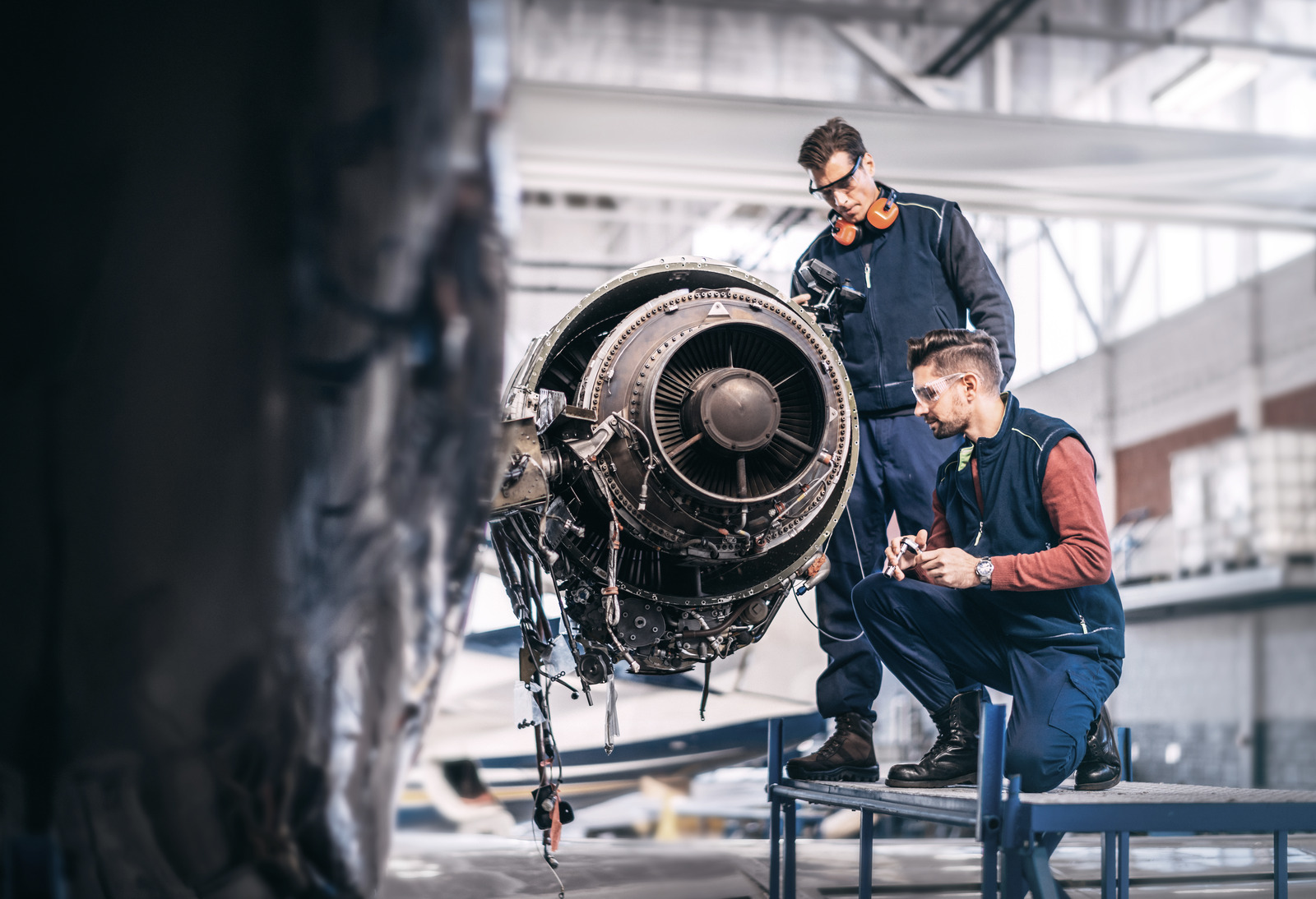 Engineers working together on a partially disassembled jet engine