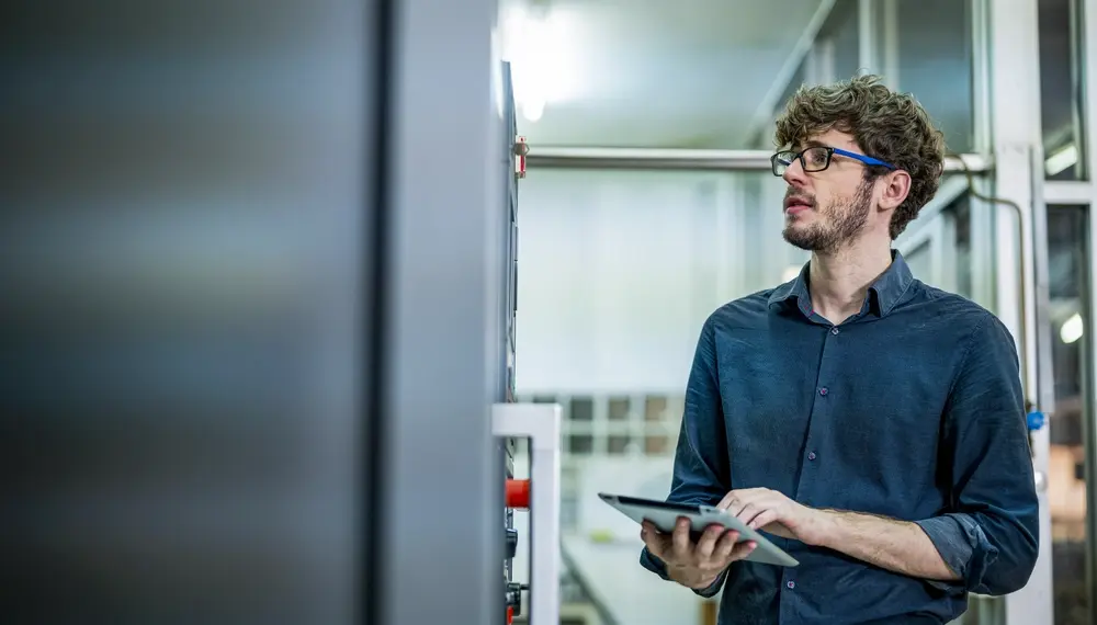 Factory operator monitoring real-time production data on a large screen on a manufacturing floor