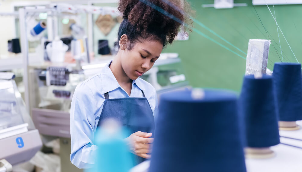 Seamstress with spools of thread in a clothing factory 