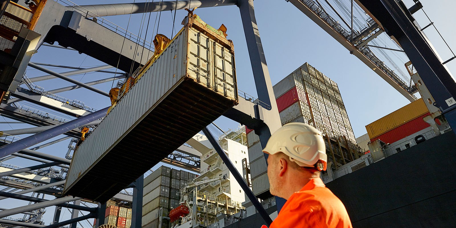 Man looking at a shipping container being offloaded 