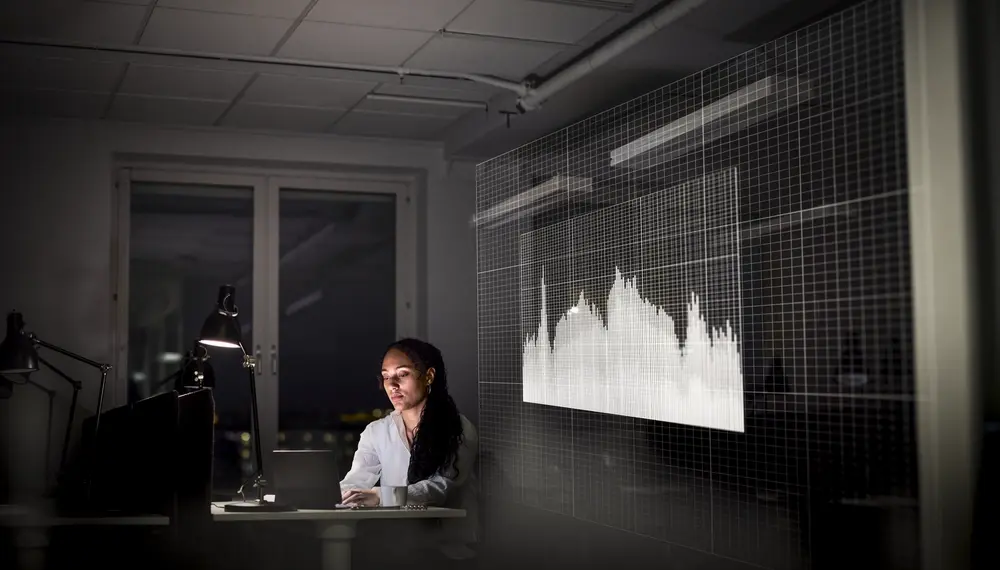 Supply chain analyst reviewing demand forecast data on a screen in a modern office setting