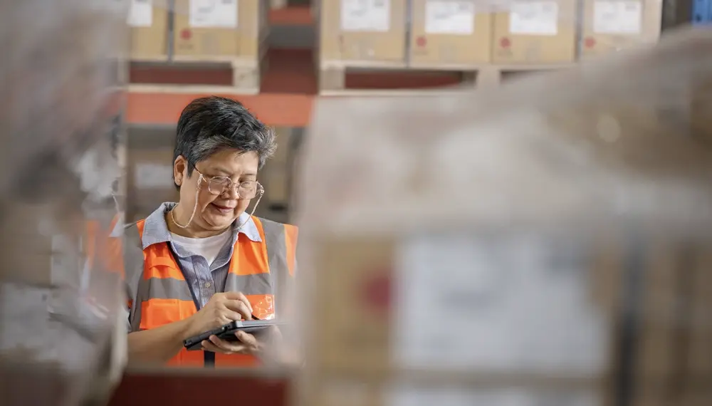 Warehouse employee checking goods, representing a connected, resilient supply chain 