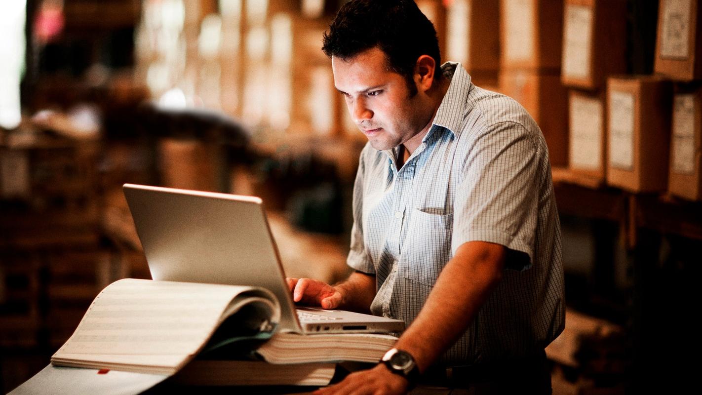 Warehouse worker using supply chain software on a laptop