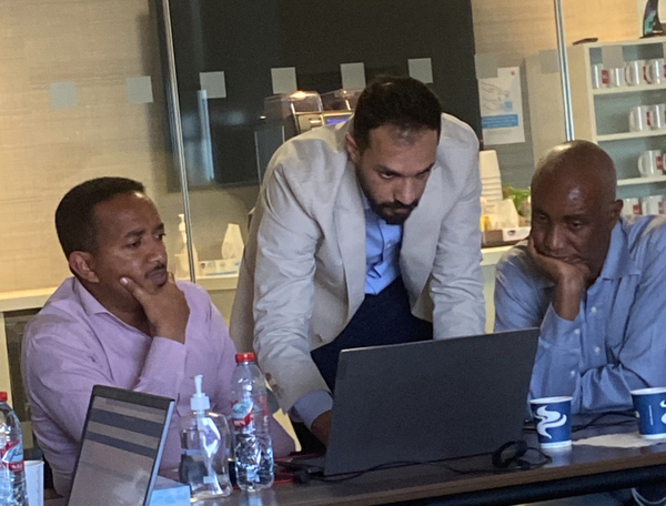 3 men studying a laptop in a darkened office