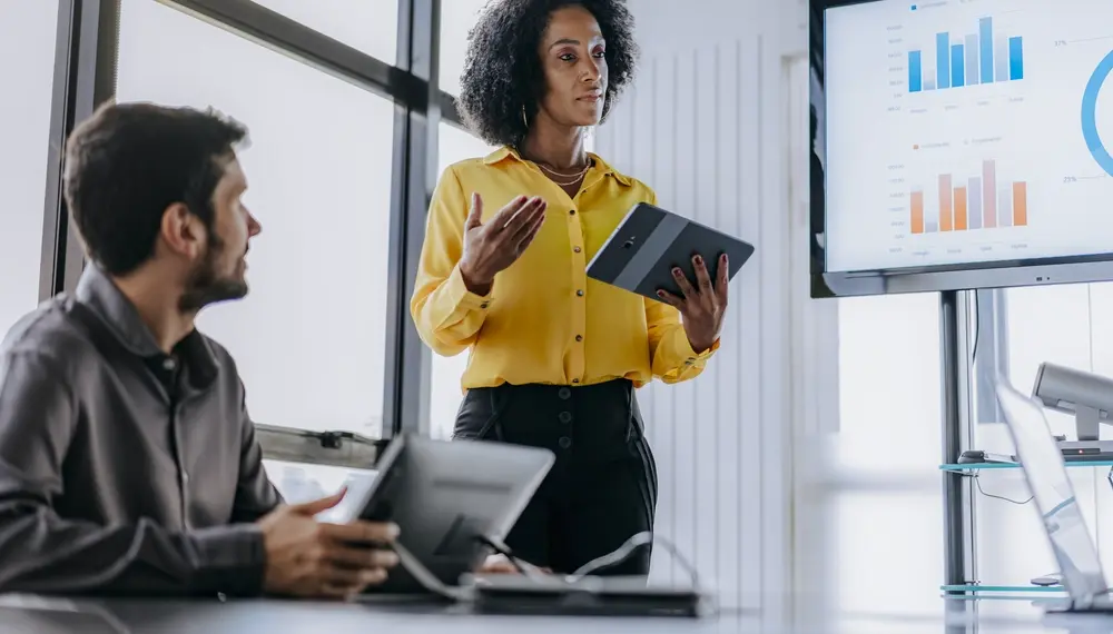 Woman holding a tablet presenting government finance reports in a meeting