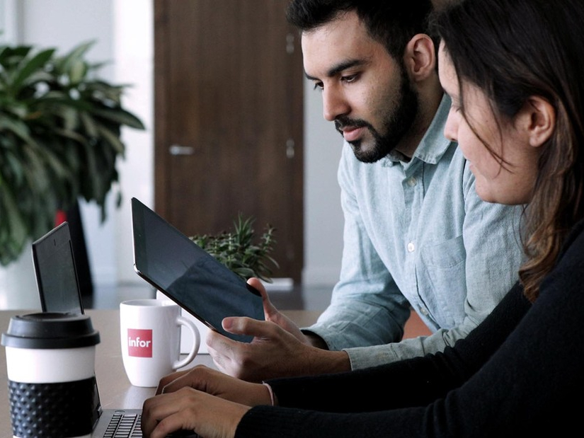 Infor employees collaborating on a tablet and laptop