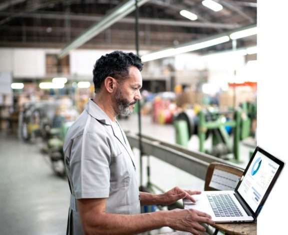 Man in front of a laptop looking at an ERP dashboard.