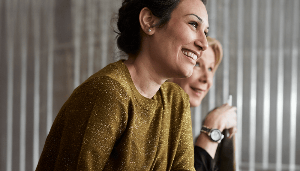 An employee smiles while talking to a colleague online  