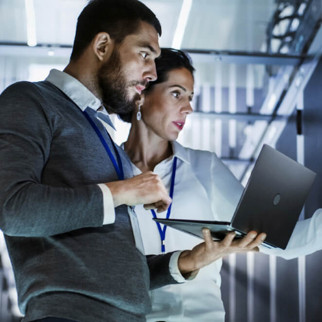 IT specialist holds laptop and discusses work with female server technician