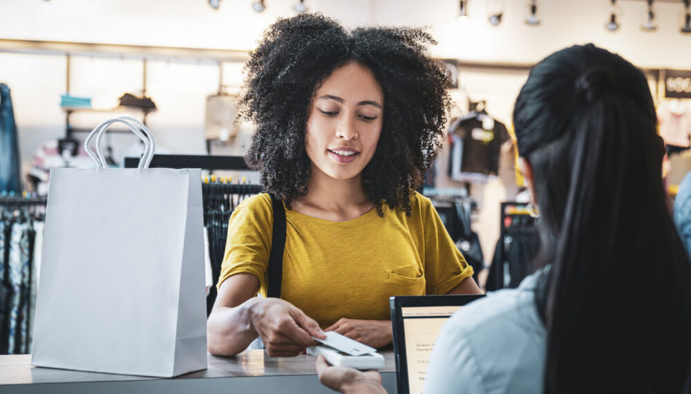 Woman happily paying by card at a clothing store