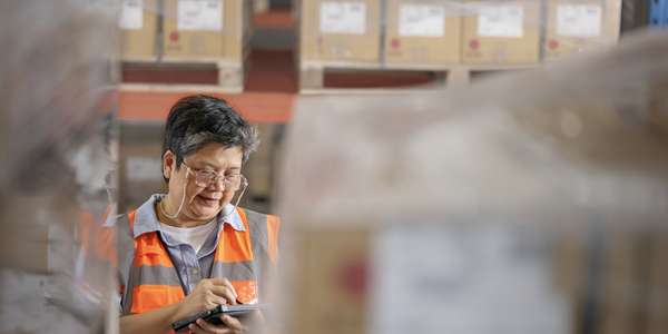 Senior warehouse manager using a digital tablet while working in a distribution warehouse