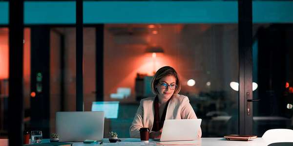 woman using a laptop at her desk late at night
