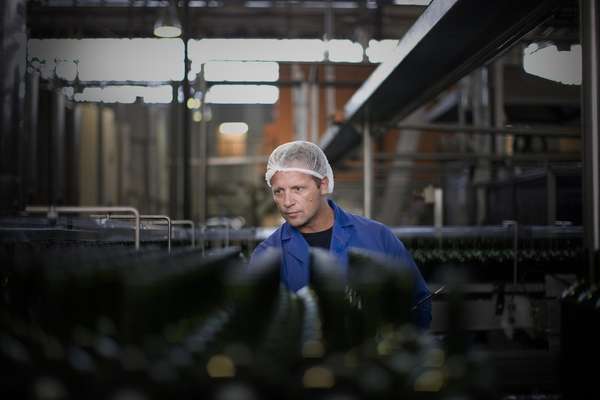 Worker examining bottles in factory 