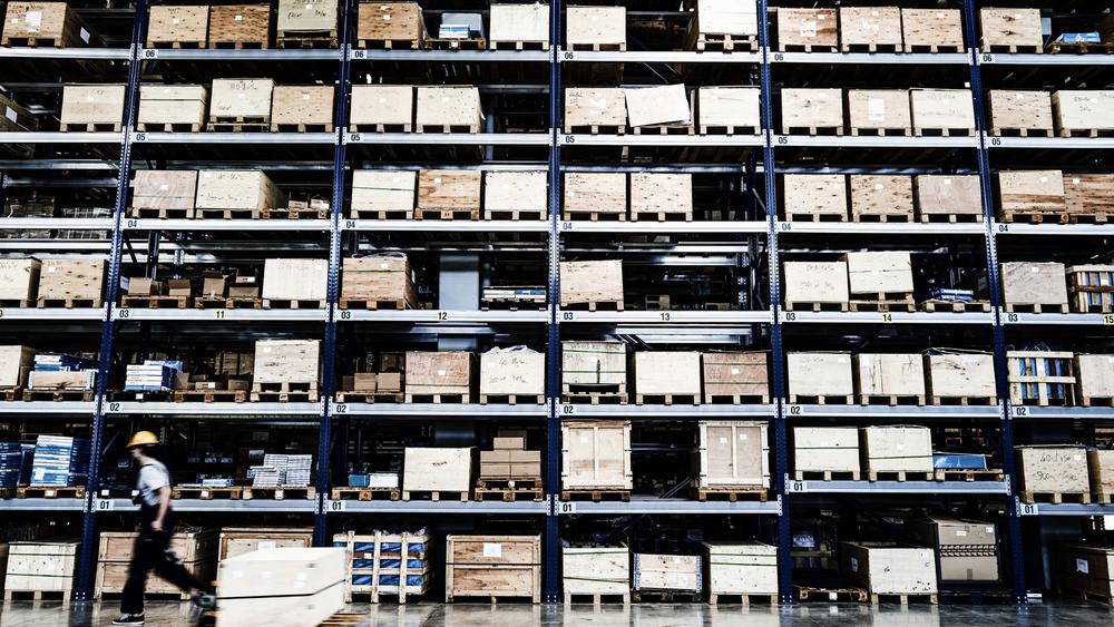 Worker moving a pallet in a large warehouse 