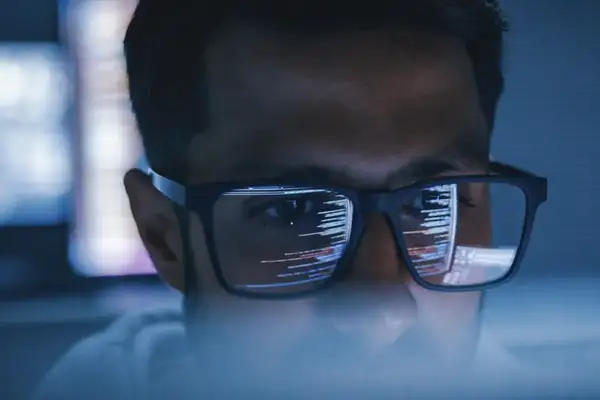 Man with glasses showing a reflection of computer code