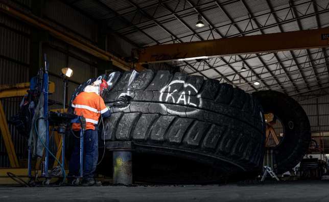 worker fixing a hole in a large equipment tire