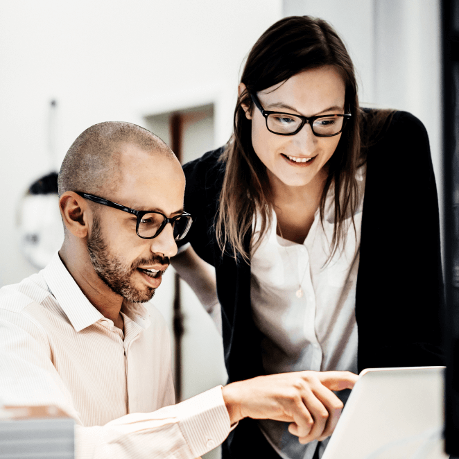 Colleagues working while looking at a laptop in a modern office 