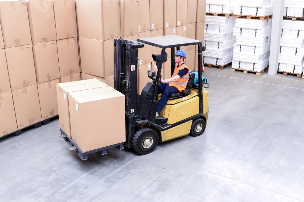 Forklift operator moving boxes in a warehouse