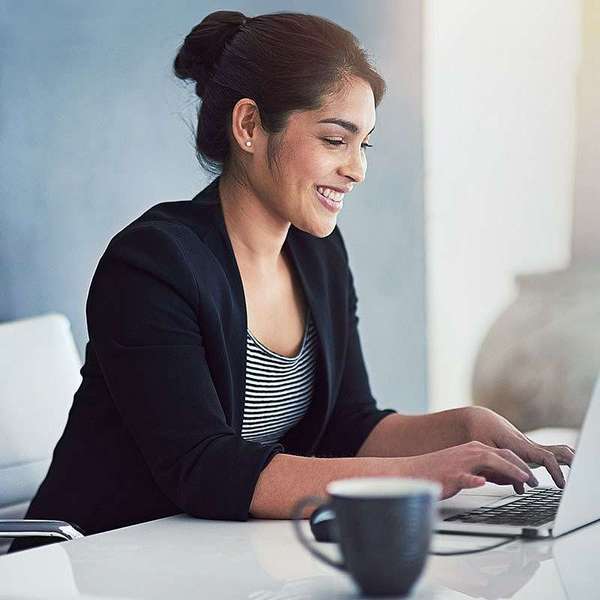 コーヒーを飲みながらノートパソコンで仕事をするプロフェッショナルな女性