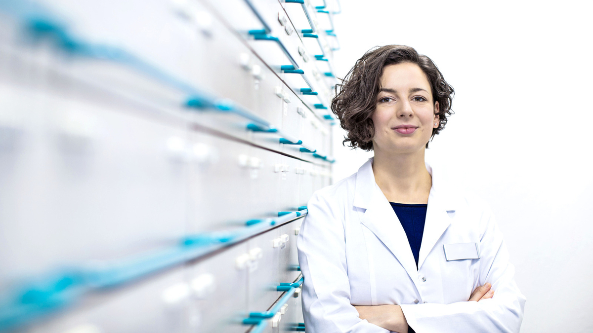 Pharmacist standing beside drawers of medications 