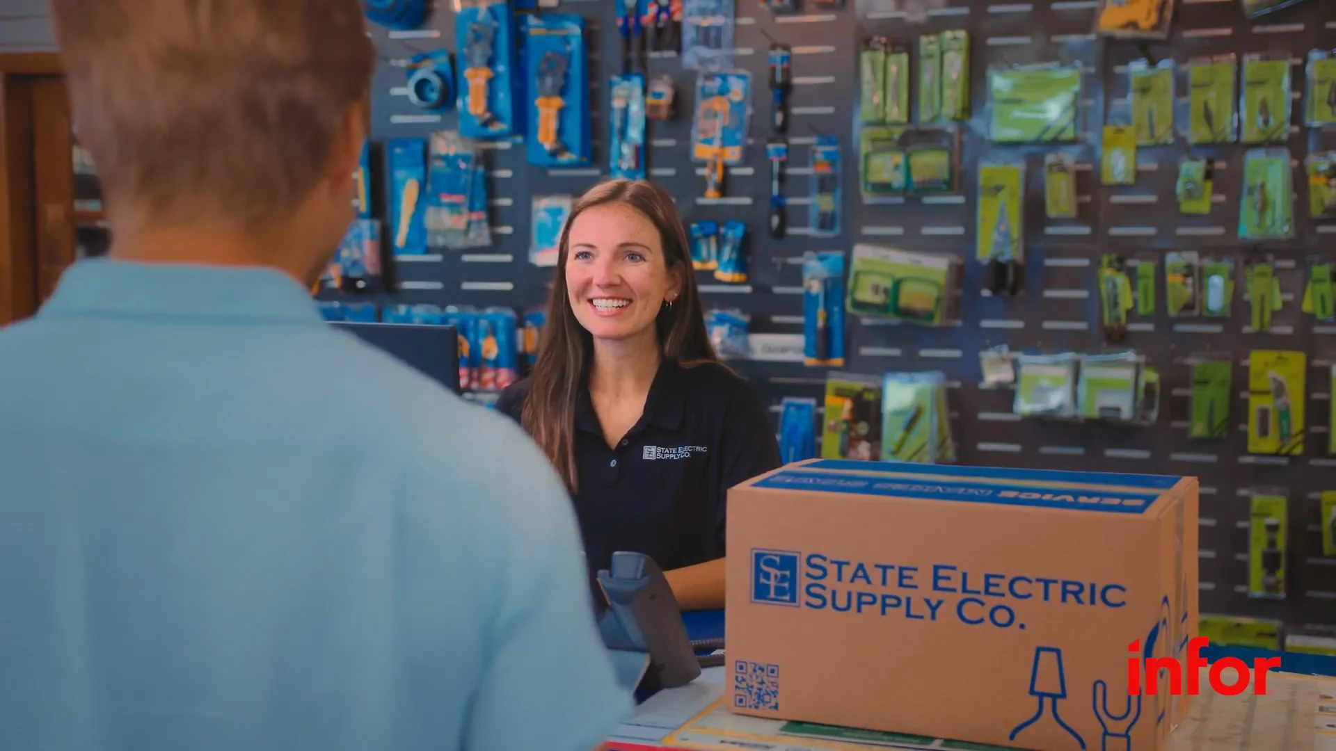 Shot of a female cashier smiling with a box from State Electric Supply Co. on the countertop