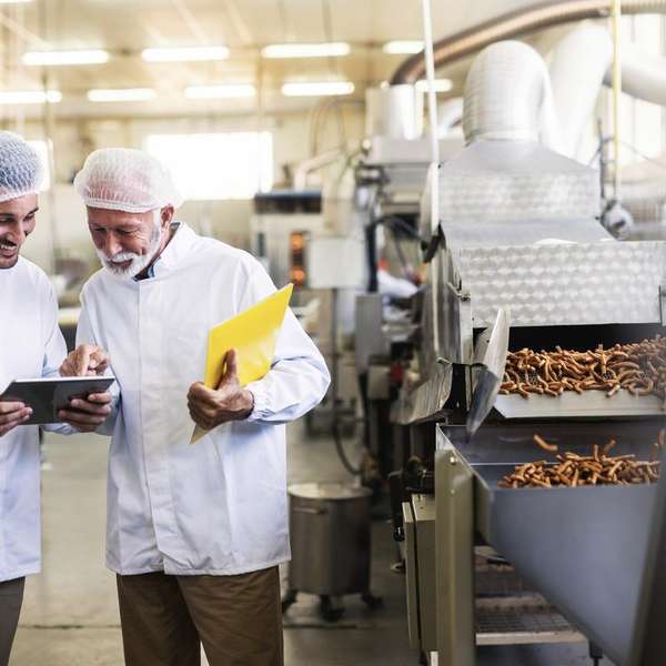 uniformes de trabajadores miran tablet de pie fábrica 