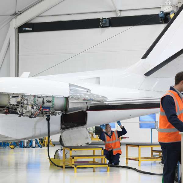 Two aerospace engineers working on a computer adjacent to a jet airplane