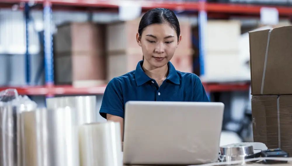 Operations planner reviewing supply data on a monitor in a warehouse environment