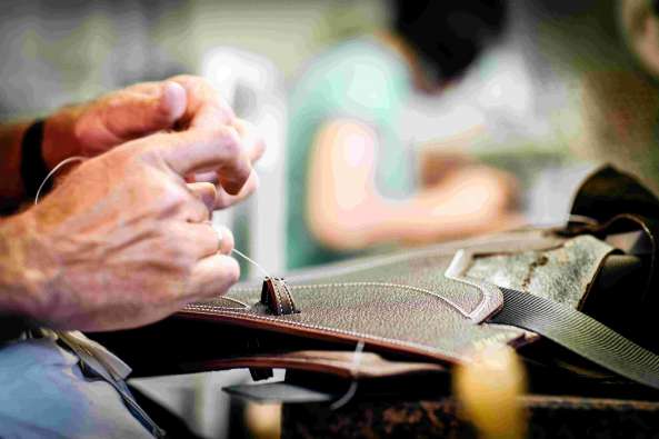 Man stitching a riding saddle