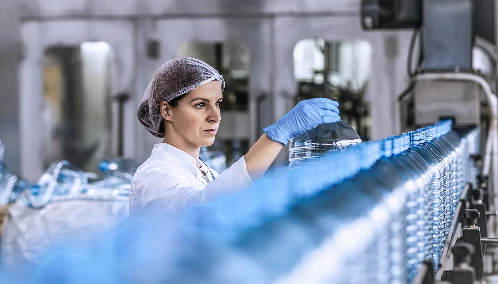 Technologist in bottling factory checking water bottles before shipment