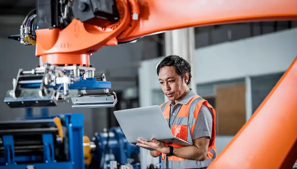 Technician operating a robotic arm in a factory 