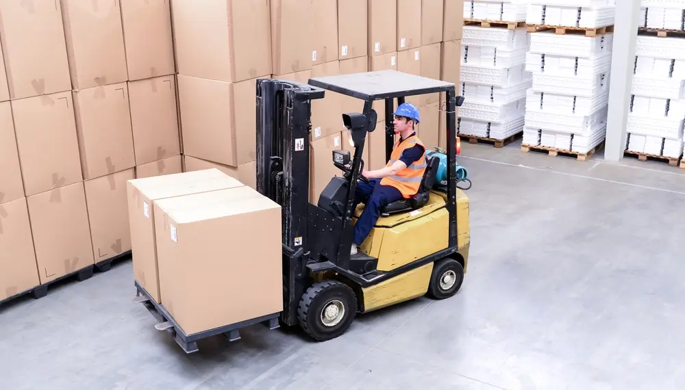 Forklift operator moving boxes in a warehouse
