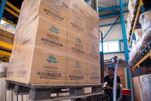 man driving forklift with pallet loaded with boxes in warehouse