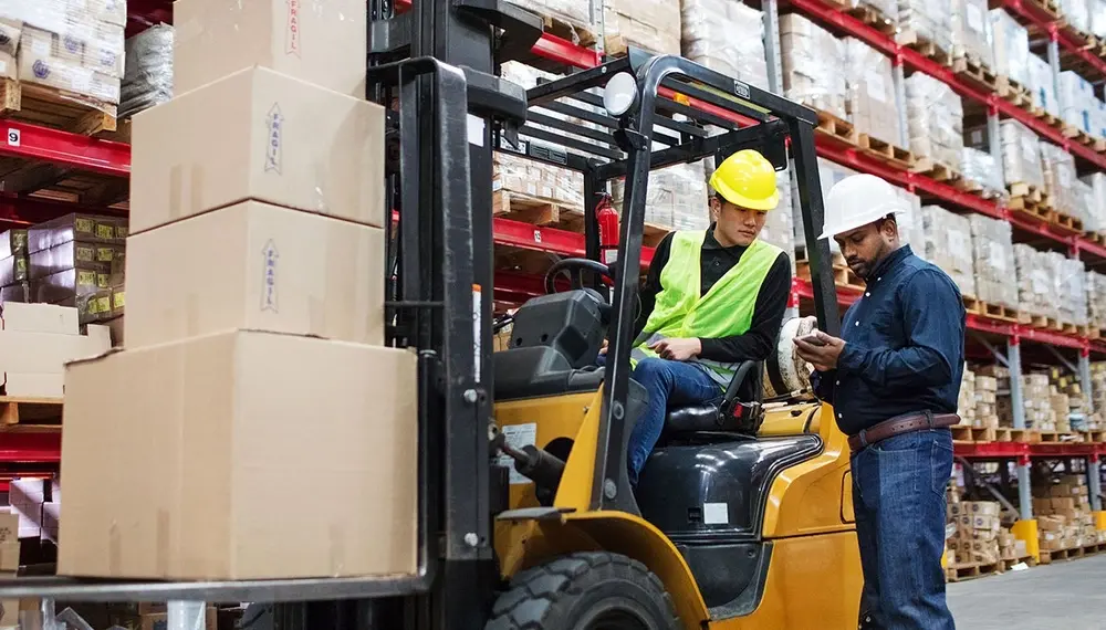 Warehouse supervisor talking to his staff while sitting in a forklift