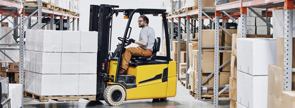 male warehouse worker driving forklift