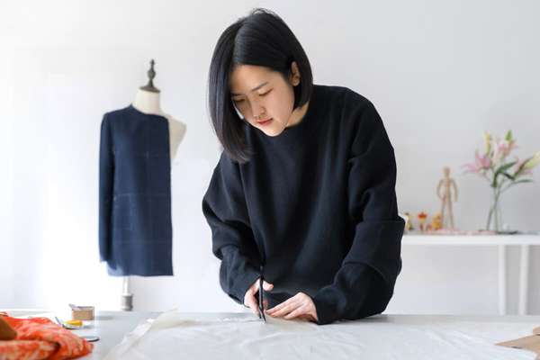 Female tailor cutting a piece of fabric at her workstation