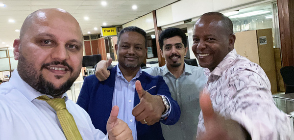 4 men smile at camera in office