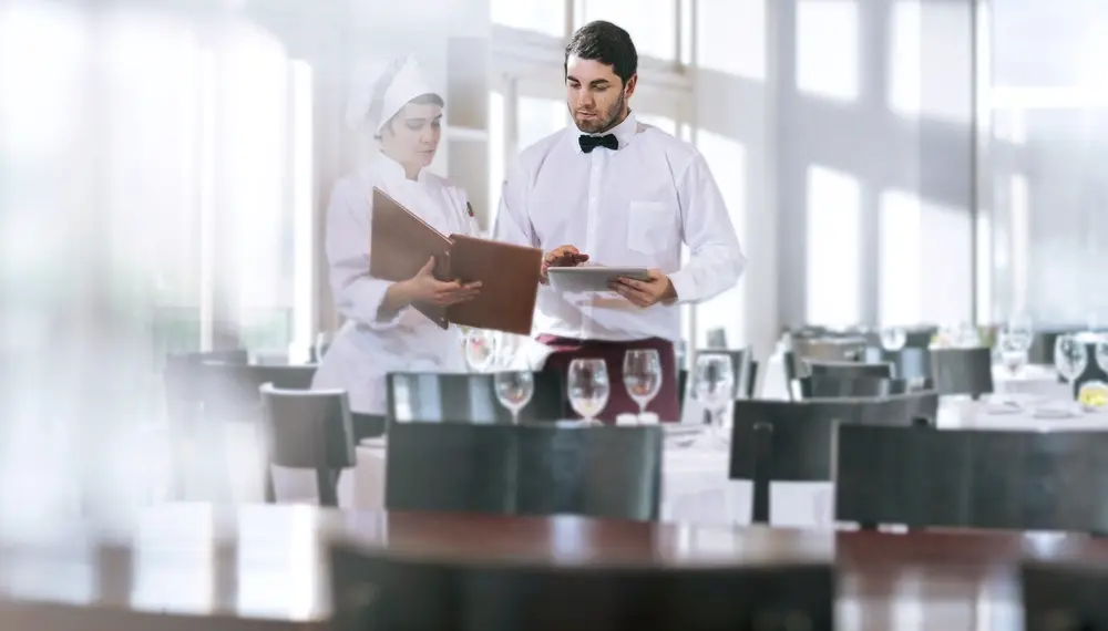 Chef and a waiter discussing a menu