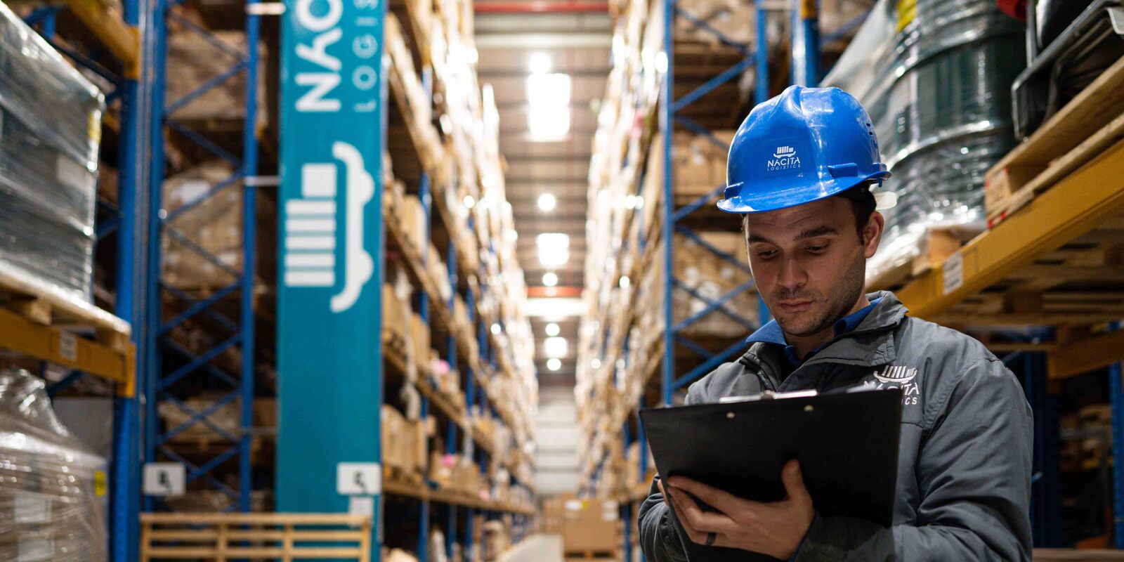 man in hardhat holding laptop in warehouse