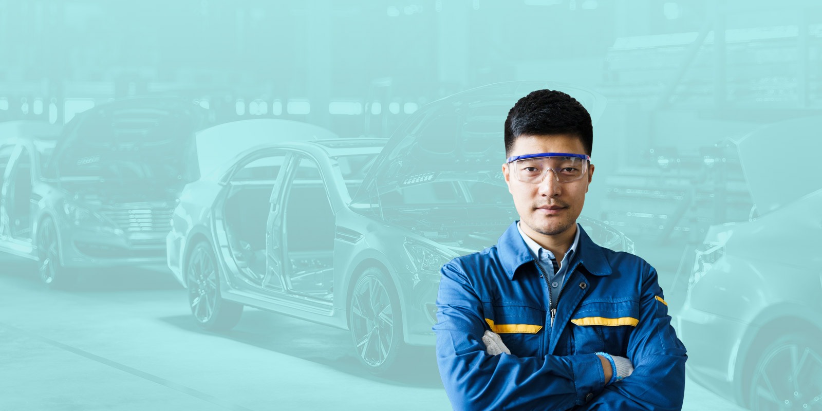 automotive worker standing in front of a factory with arms crossed