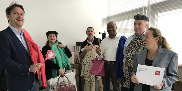 2 women and 3 men hold clothes and bags in office