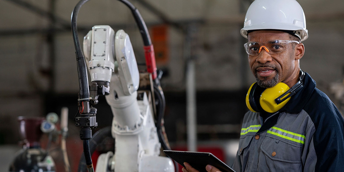 man working in a factory wearing white hard hat